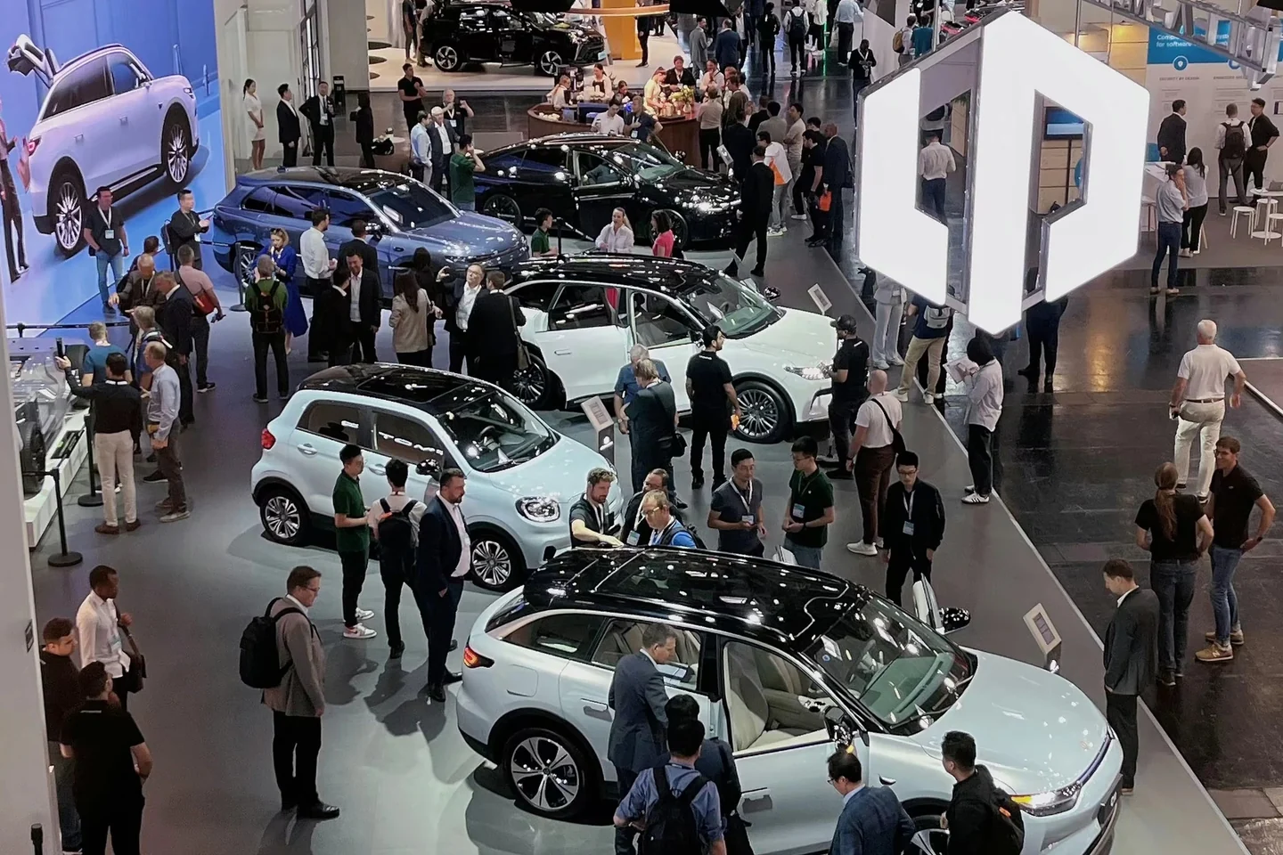 Visitors and vehicles at an international motor show, representing real automotive market research context